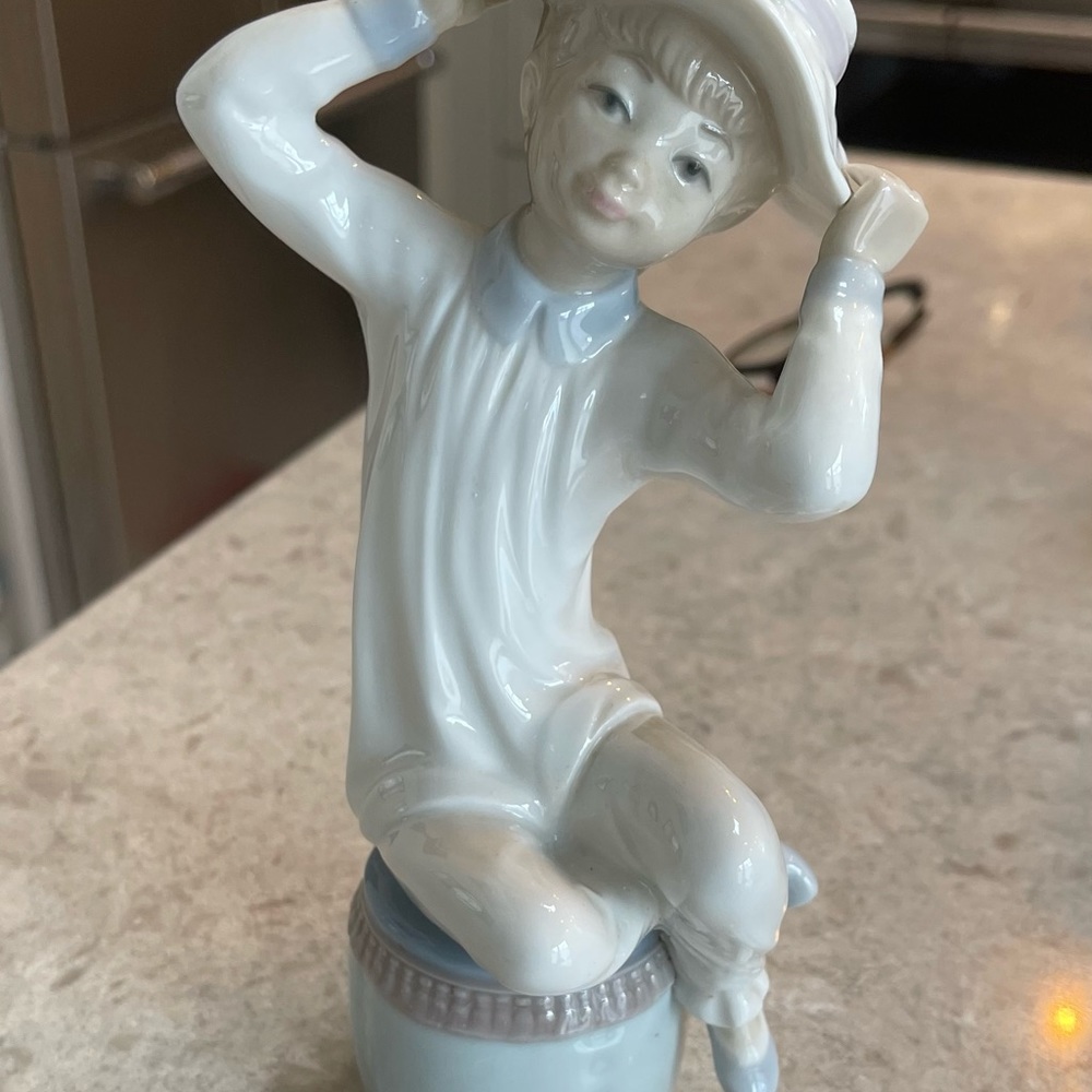 Lladro Woman suiting on a stool holding her hat.